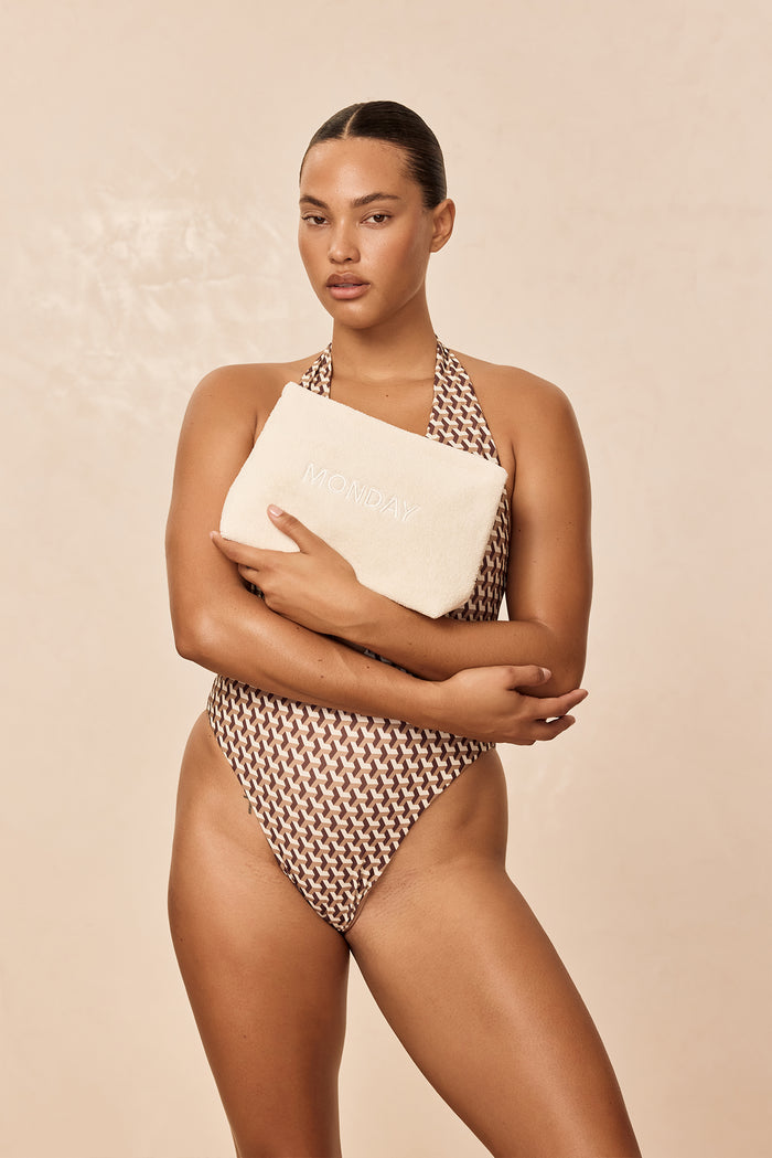 Front view of Monday Sunscreen Bag showing ivory terry fabric and tonal MONDAY embroidery held by model against a beige background
