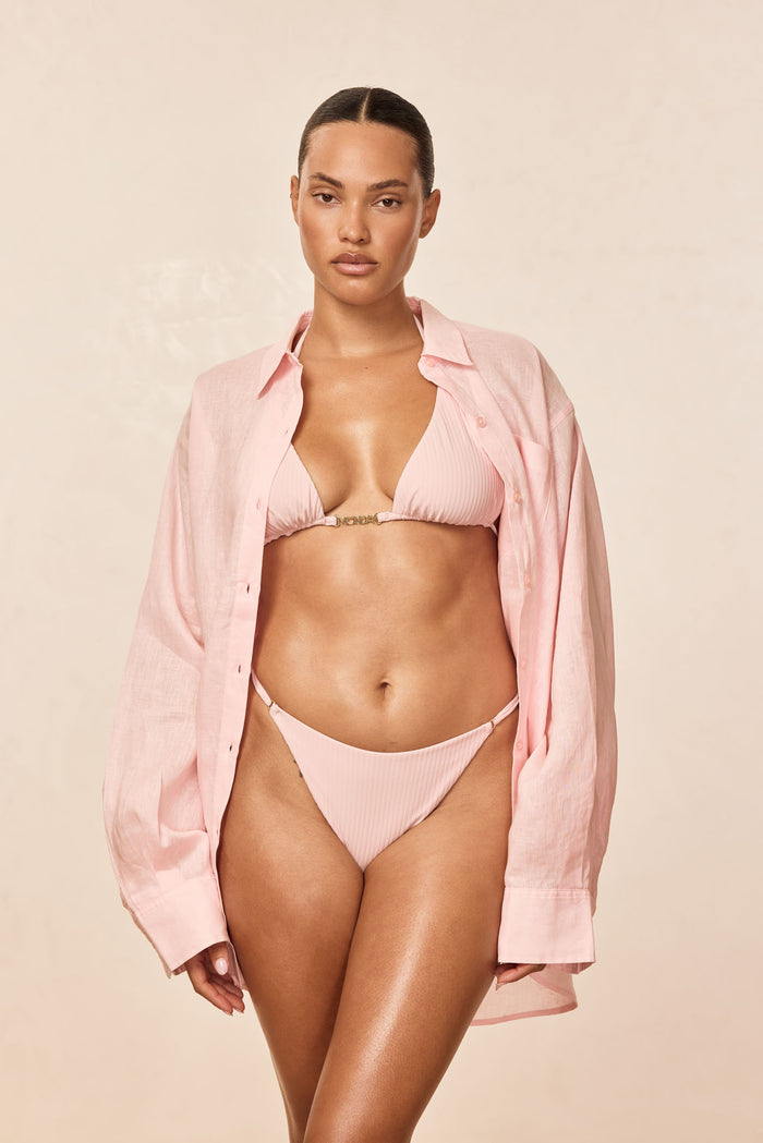 Front view of Monday Top - Powder Pink Rib showing ribbed triangle cups and gold MONDAY center hardware on beige background