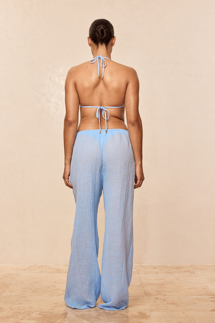 Rear view of Monday Top in Sky Rib showcasing halter and back tie with gold hardware on model against beige background