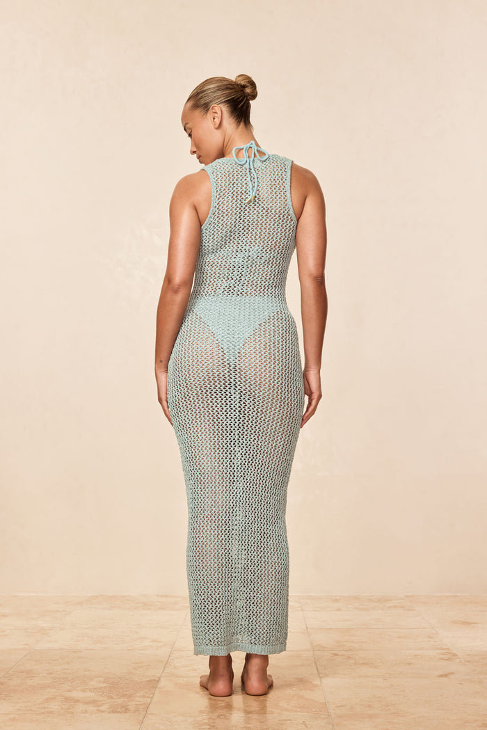 Back view of Monte Carlo Tie Dress in light slate crochet, form fitting with tie neck and sheer skirt on neutral background