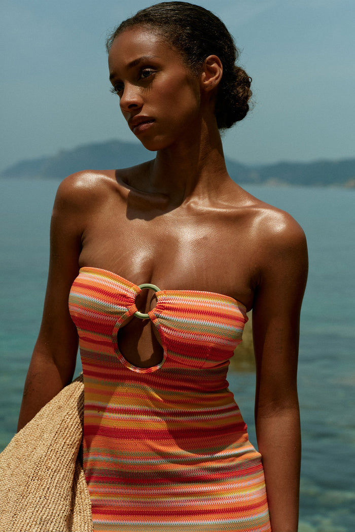 Three-quarter front of Montego Bandeau Dress in Sardinia Stripe showcasing front ring cutout and strapless bandeau fit at seaside