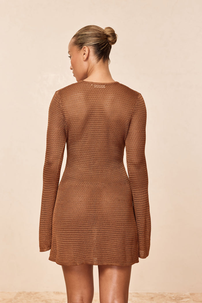 Back view of Montego Mini Dress in caramel knit showing long sleeves, open weave and fitted waist on beige background