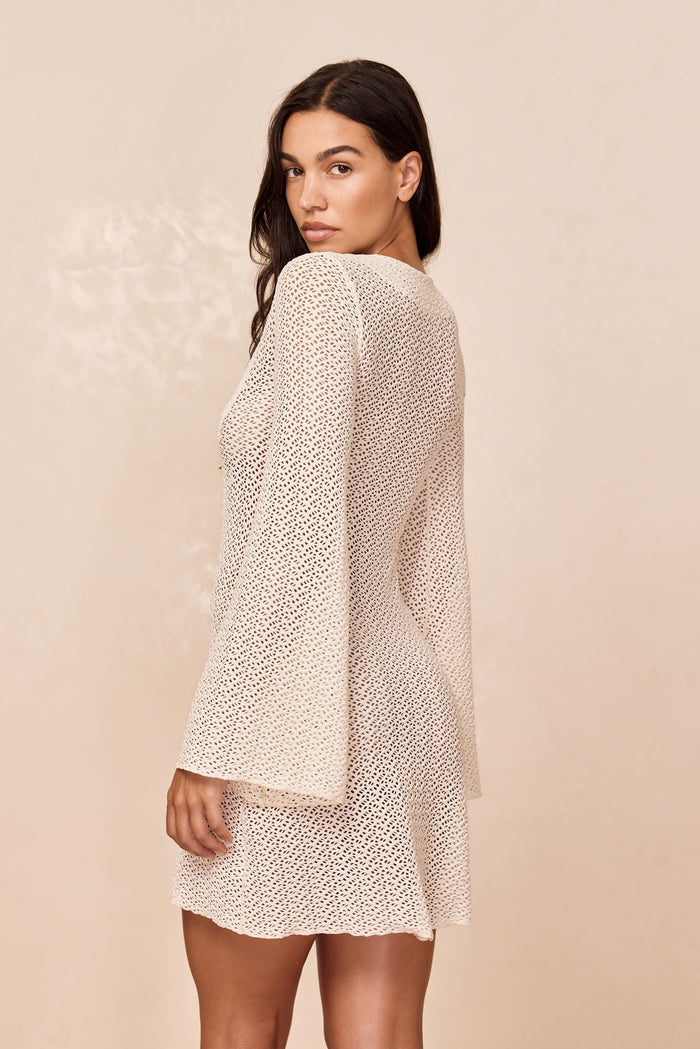 Rear three-quarter of Montego Mini Dress in ivory crochet showing open-knit texture, bell sleeves, and mini skirt
