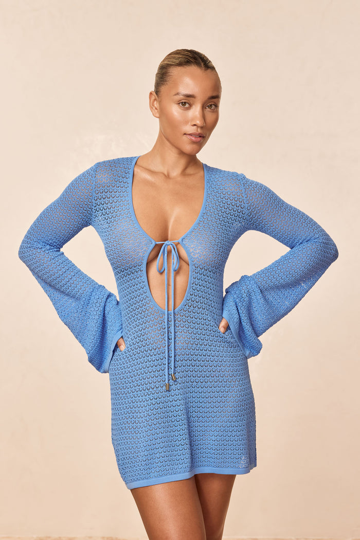 Front view of Montego Mini Tie Dress in azure lace crochet with keyhole front tie, long bell sleeves and mini length on model