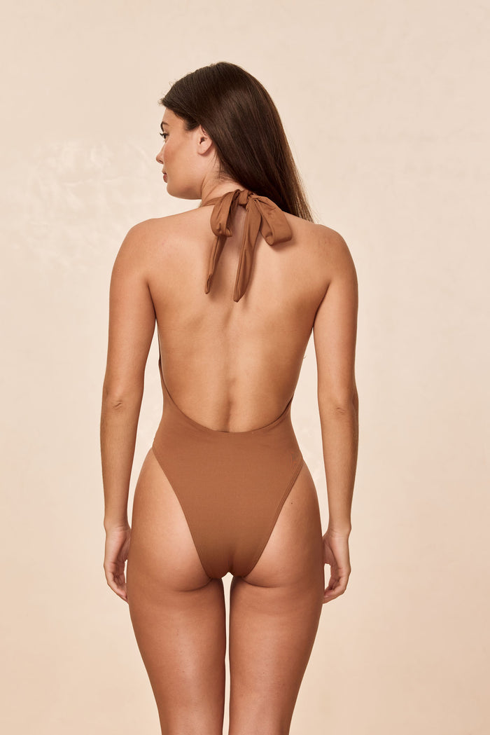 Rear view of Montego One Piece in caramel showing halter neck tie, low scooped back and high-cut leg on beige background