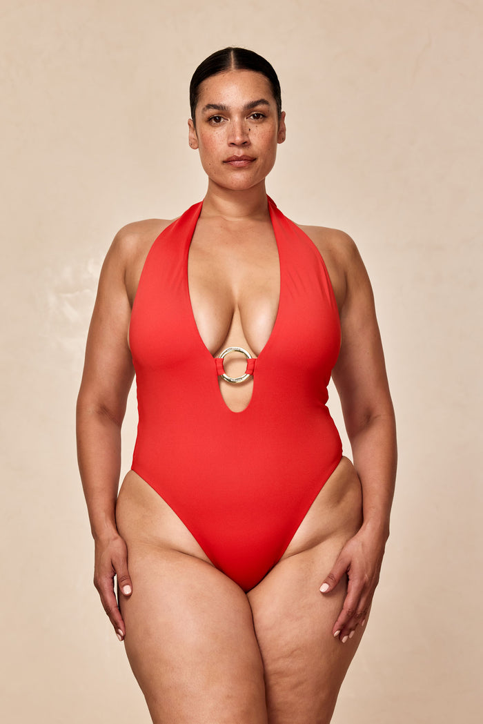 Front close-up of Montego One Piece in Chili Pepper showing plunging halter neckline, gold ring detail and high-cut leg on neutral background