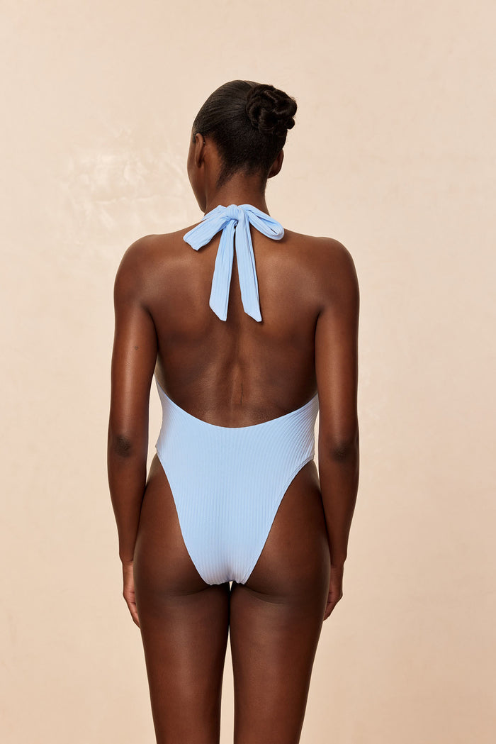 Back view of Montego one-piece swimsuit in Sky Rib with low back, halter tie, high-cut leg, ribbed texture on beige background