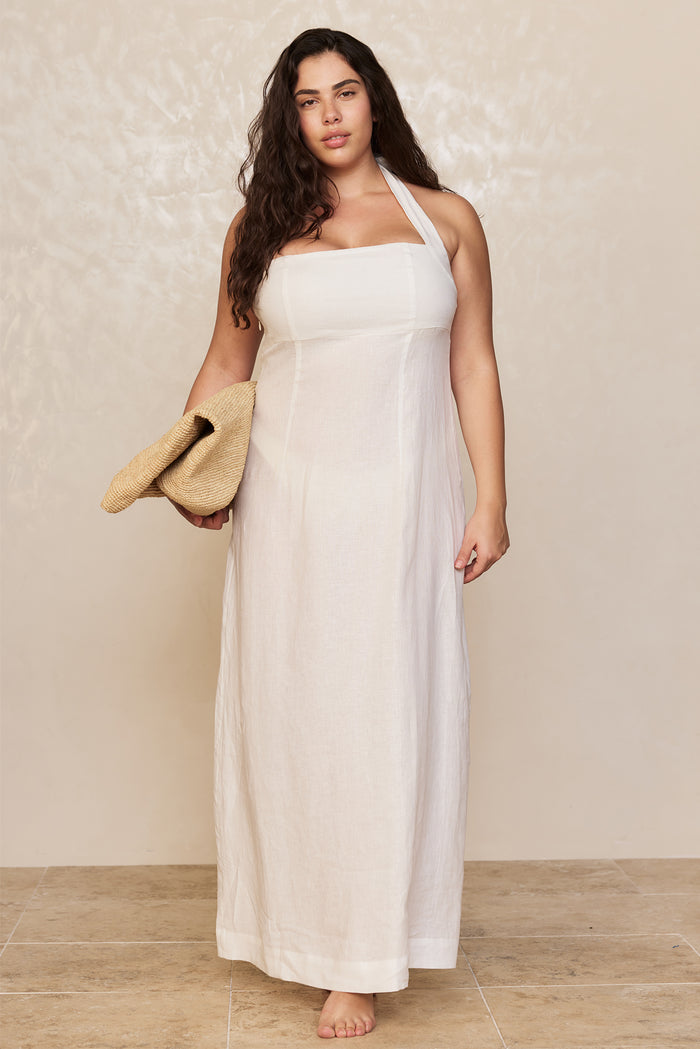 Front view of Montserrat Dress in white linen showcasing halter neckline and fitted bodice with neutral backdrop