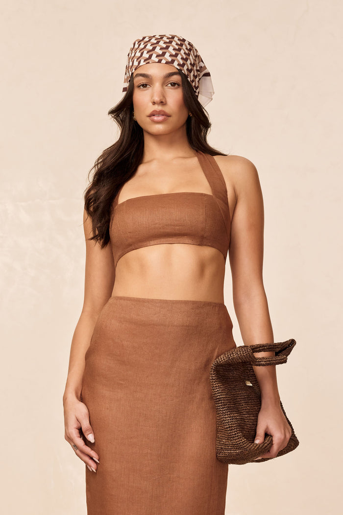 Front view of Montserrat Top in caramel linen bandeau with wide halter strap on model against neutral background