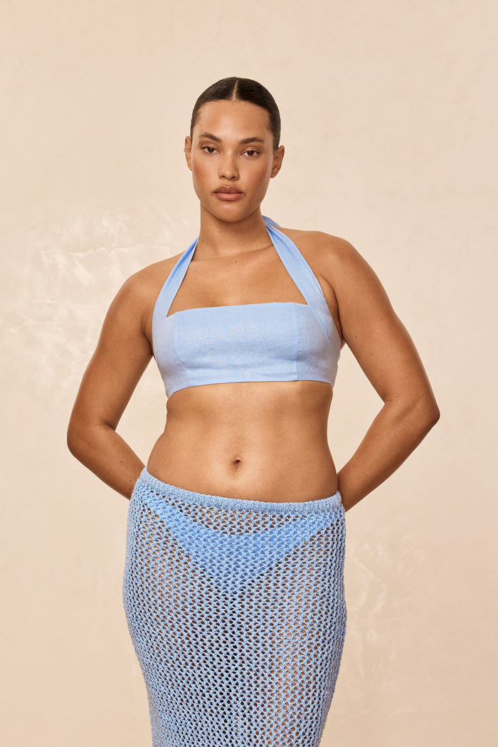 Front view of Montserrat Top in Sky Linen on model, showcasing halter neckline, lined bust and cropped fit on beige background