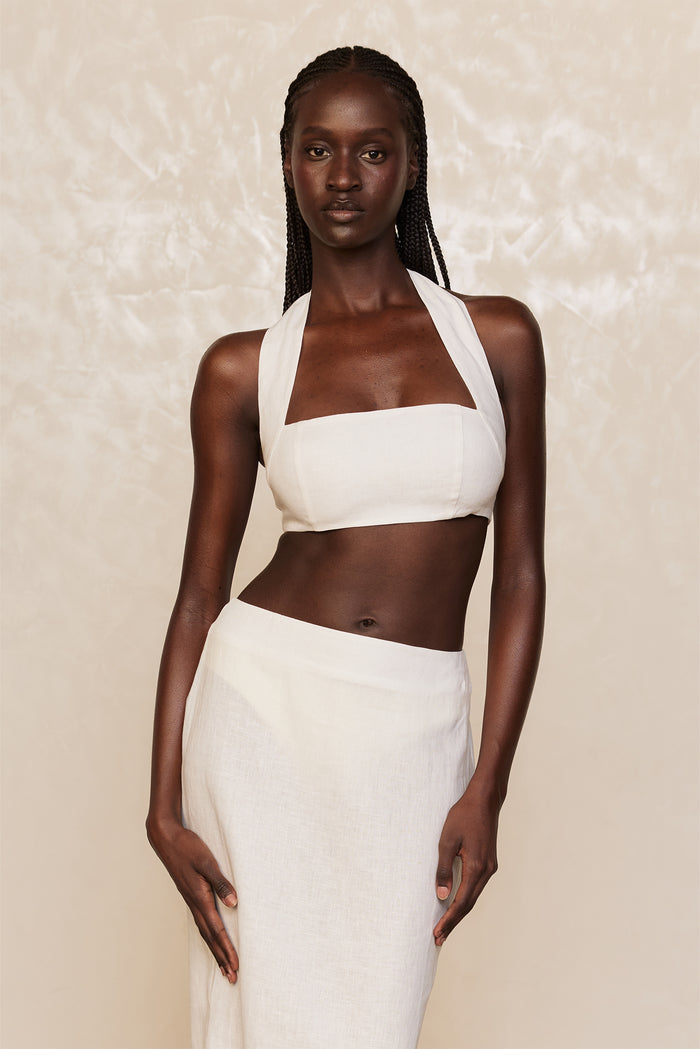 Front view of Montserrat Top in White Linen showing halter neckline and cropped fit with matching skirt on pale textured backdrop