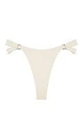 Flat lay of Morocco Bottom in Ivory showcasing high-cut silhouette, side tie straps and gold ring hardware on white
