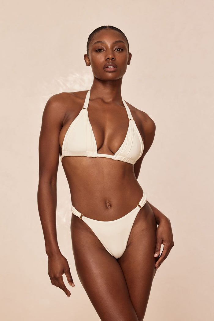 Front view of Morocco Bottom in ivory on model showcasing high-cut silhouette and gold ring hip accents against a neutral beige background