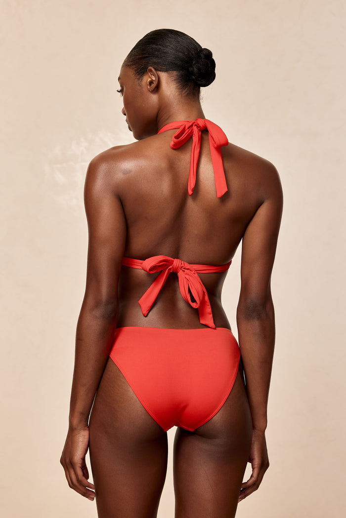 Back view of Seychelles bottom in Chili Pepper showing modest coverage on model against neutral beige background