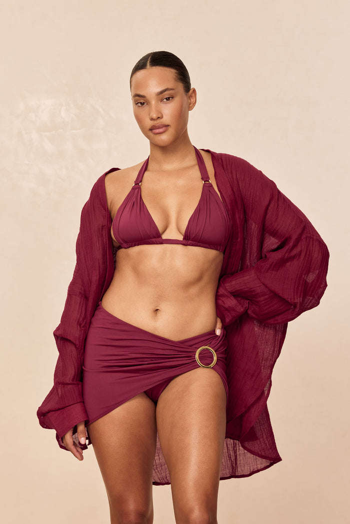 Front view of Morocco Top in Fig showing pleated cups, gold ring hardware and adjustable ties, model on beige background
