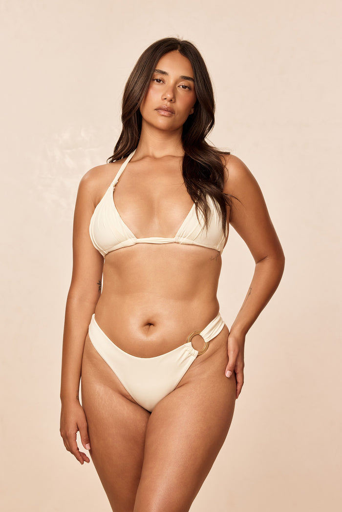 Front view of Morocco Top in ivory on model showcasing ruched triangle cups and tie-neck halter straps with beige background