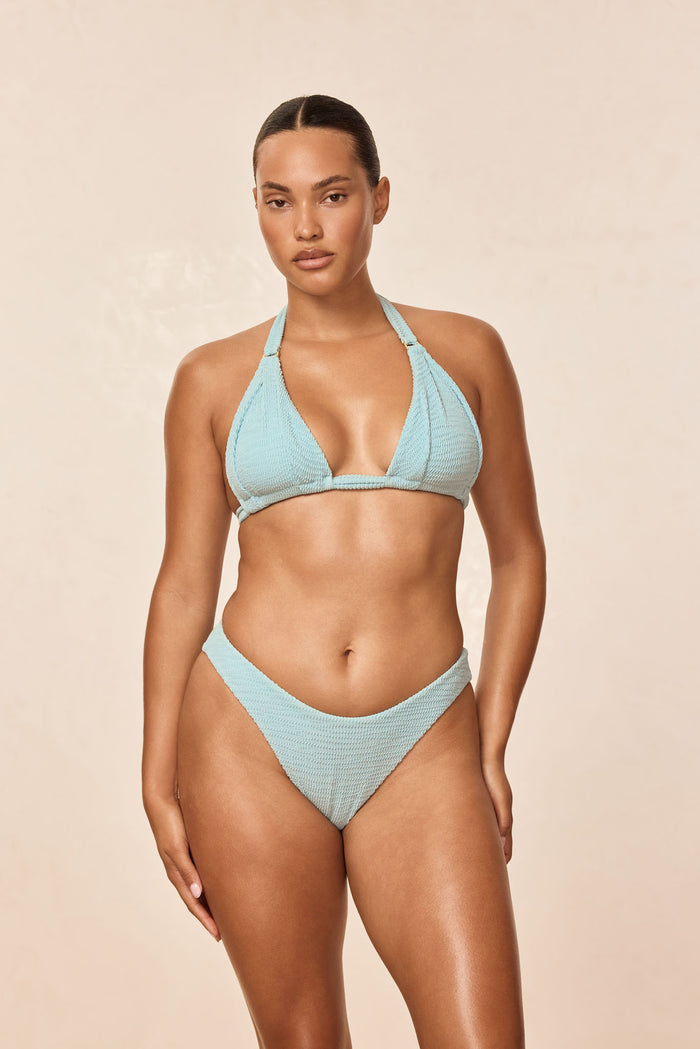 Front view of Morocco Top showcasing light slate crinkle triangle halter with gold rings on beige background