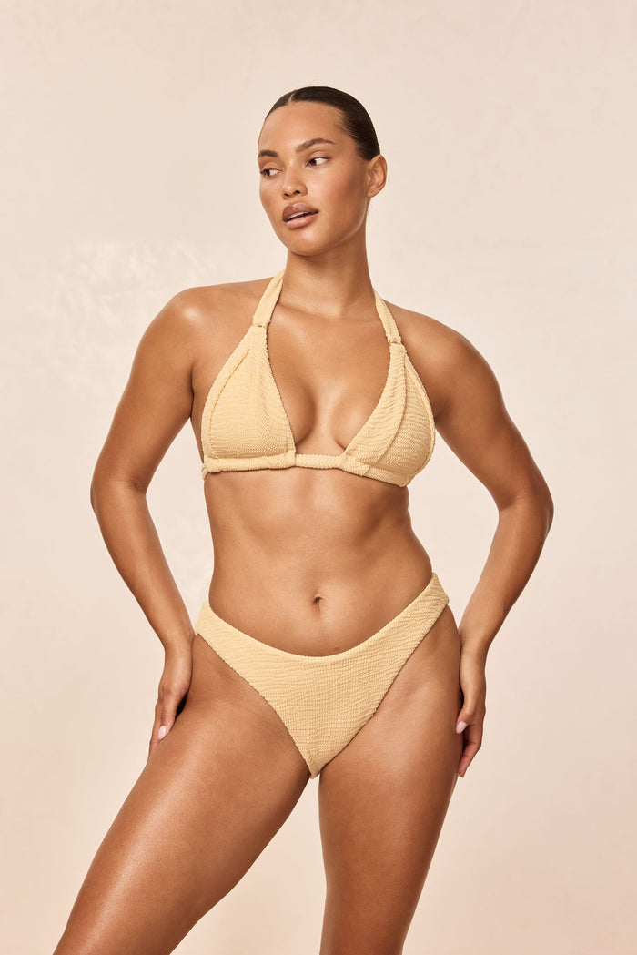 Angled front view of Morocco Top in Raffia Crinkle on a model, showing pleated cups, gold ring hardware and adjustable ties