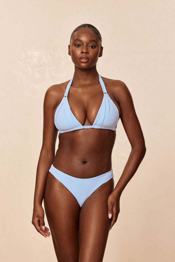 Front view of Morocco Top in Sky Rib on model showcasing ribbed fabric, gold rings and halter ties against beige background