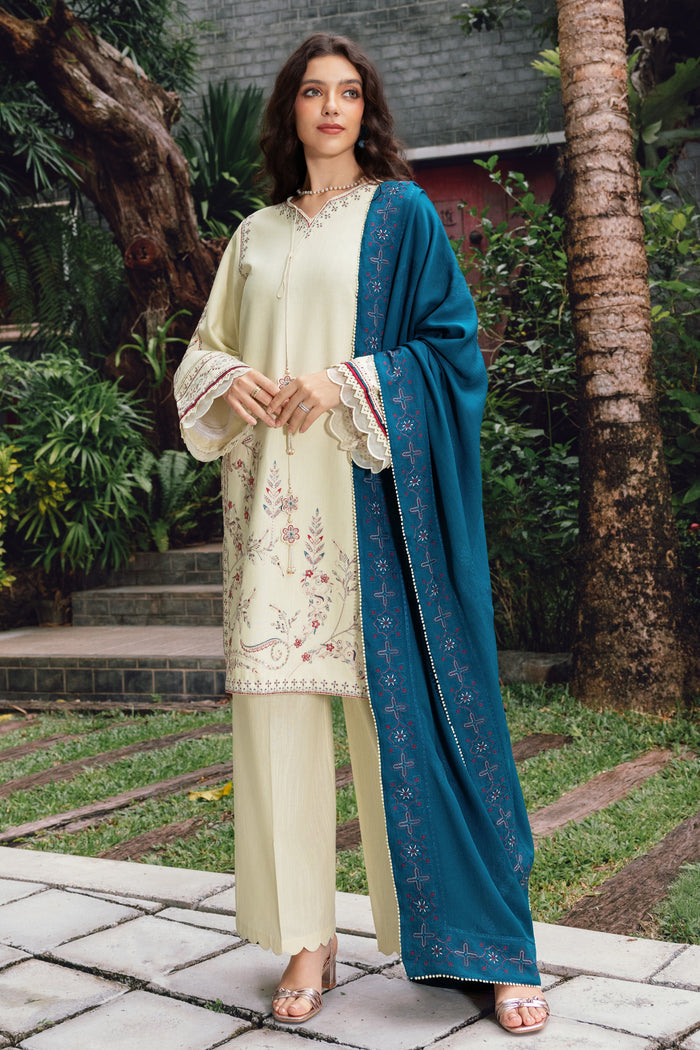 Woman wearing a cream embroidered outfit with a blue dupatta in an outdoor setting.