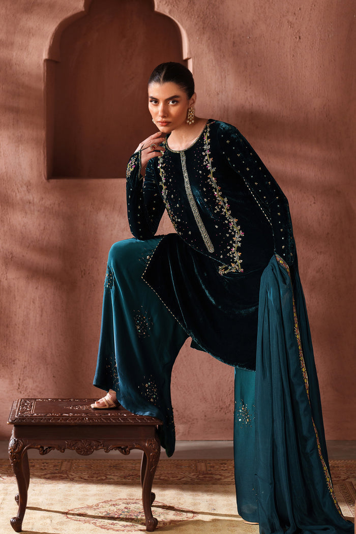 Seated styling view of NAQSHI teal green ready-to-wear formal outfit with embroidered shirt and matching trousers