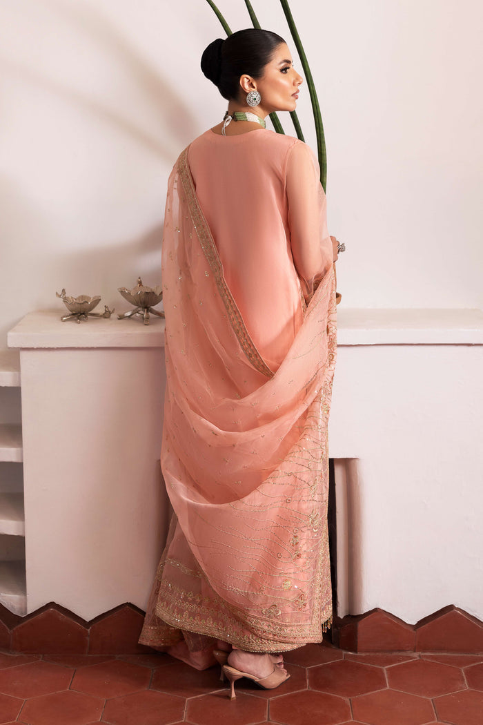 Side profile of NAQSHI Muzna showcasing flowy organza gown silhouette, embroidered V‑neck panel, fluid side slit, crystal‑trim sleeve ends and silk trousers.