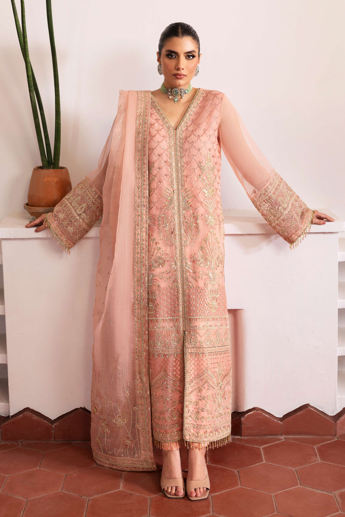 Model wearing full NAQSHI Muzna set: flamingo‑pink embroidered organza gown, straight PK‑silk trousers & heavily detailed dupatta styled for a cohesive look.