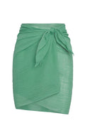 Green lightweight wrap skirt with tied side knot and frayed edges, sarong-style knee-length overlay.