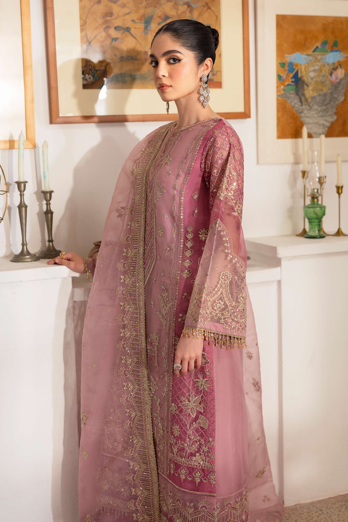 Side look at NAQSHI Nayab showing organza shirt silhouette with berry-pink embroidered side panels, crystal hangings on sleeves, and matching culottes.