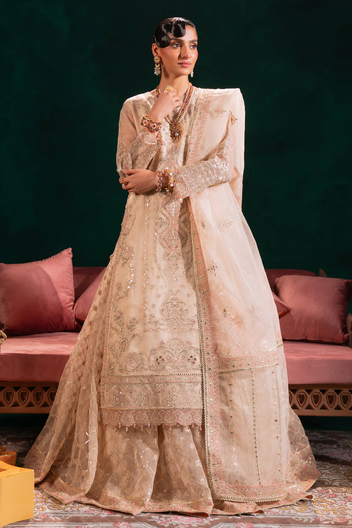 Naqshi Nigaar beige‑pink organza long shirt with boat neckline and dangling crystal tassels on sleeves and sides, paired with heavily embroidered sequin‑work lehenga and ornate dupatta.