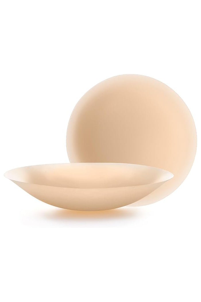 Front and side views of Nippies adhesive nipple covers showing thin, rounded, flesh-toned stick-on cups on a white background