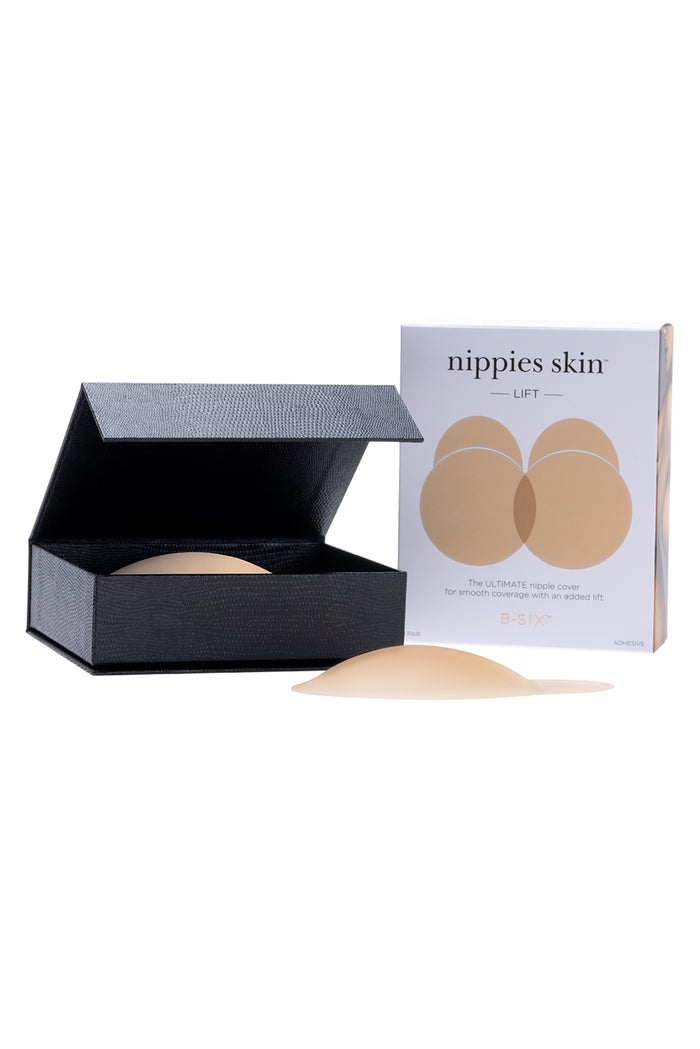 Angled view of Nippies Skin Lift silicone nipple covers and box showing domed adhesive lift and black storage case on white background