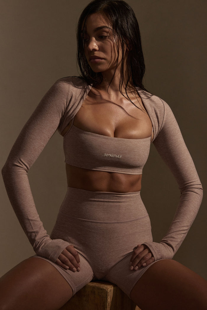 Front view of Olympic Bra in heather mauve showcasing bandeau silhouette, MONDAY logo and matching shrug sleeves on a seated model
