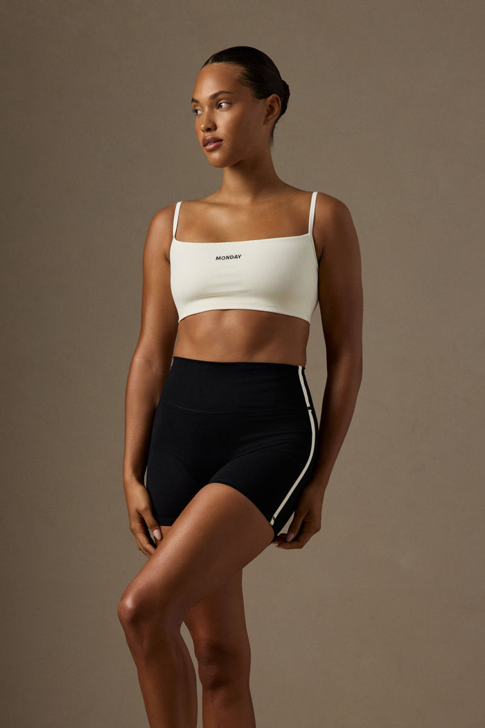 Front view of Olympic Bra in ivory showcasing scoop neckline, adjustable back straps and MONDAY embroidery on a neutral background