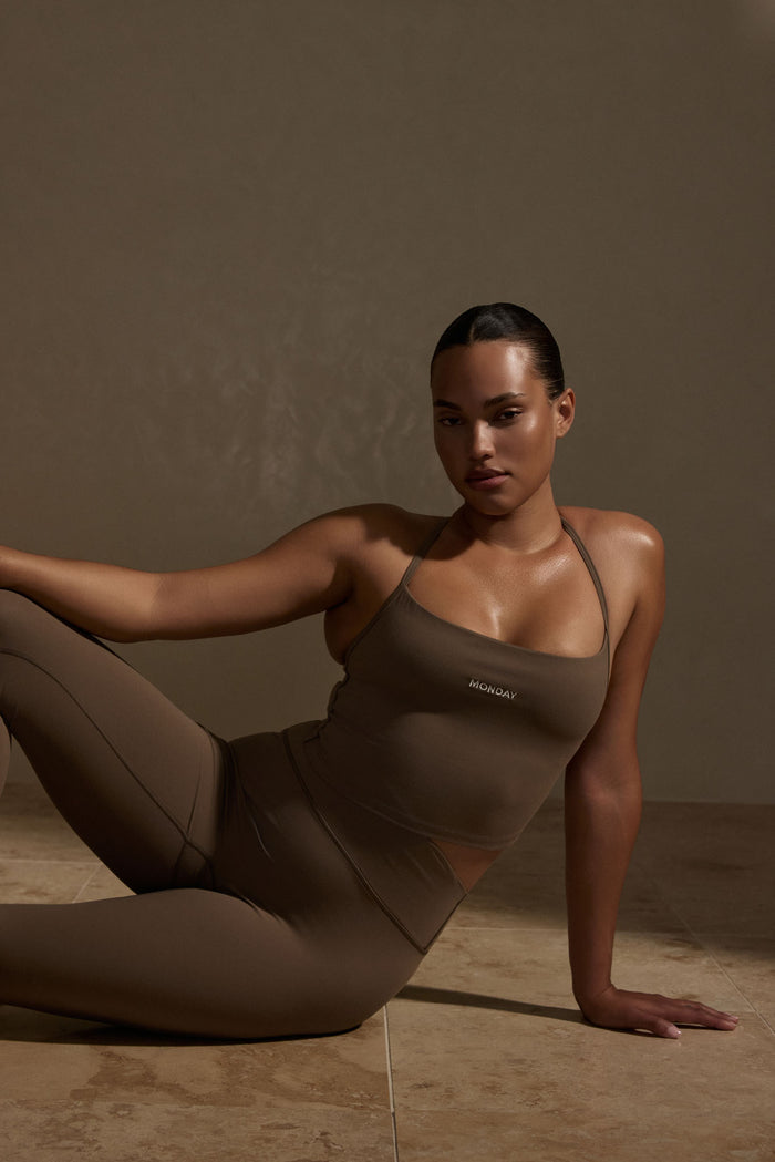 Seated view of Olympic Tank in Stone Jersey showing scoop neckline, thin straps, cropped fit and MONDAY embroidery