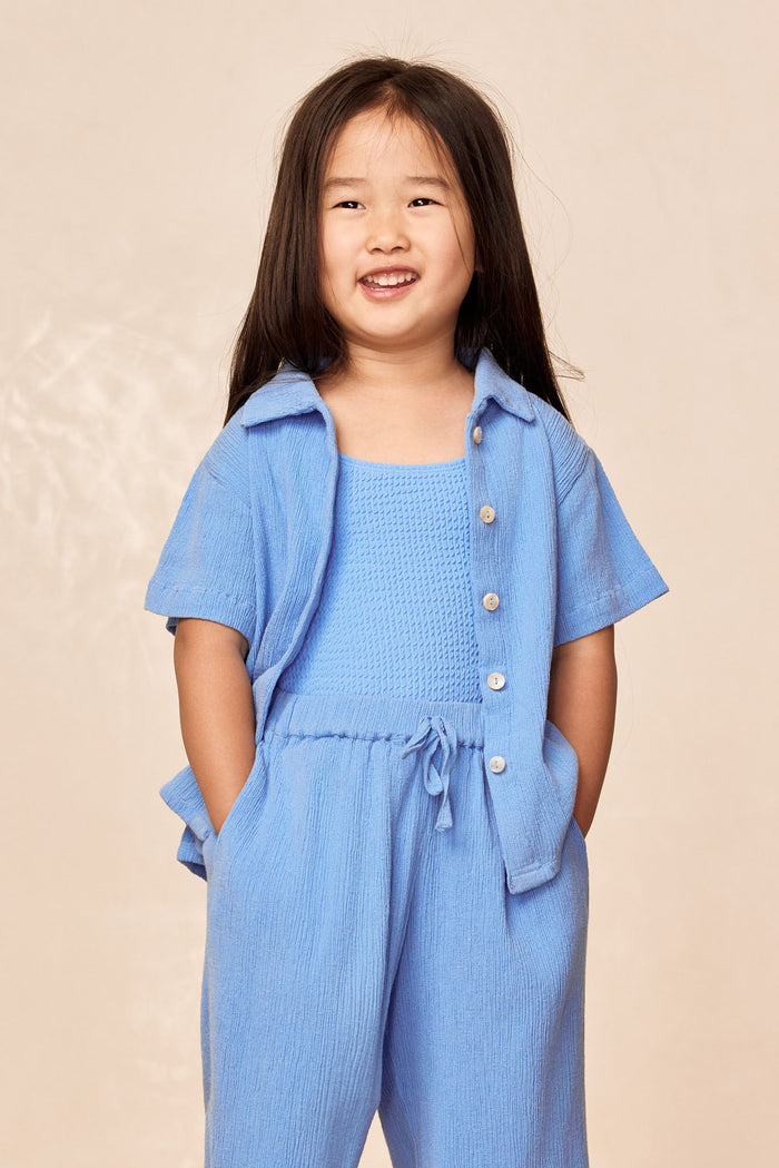 Front view of Pacific Beach Shirt Kids in Azure Crinkle showcasing short-sleeve button-front crinkle fabric on a child model with beige background