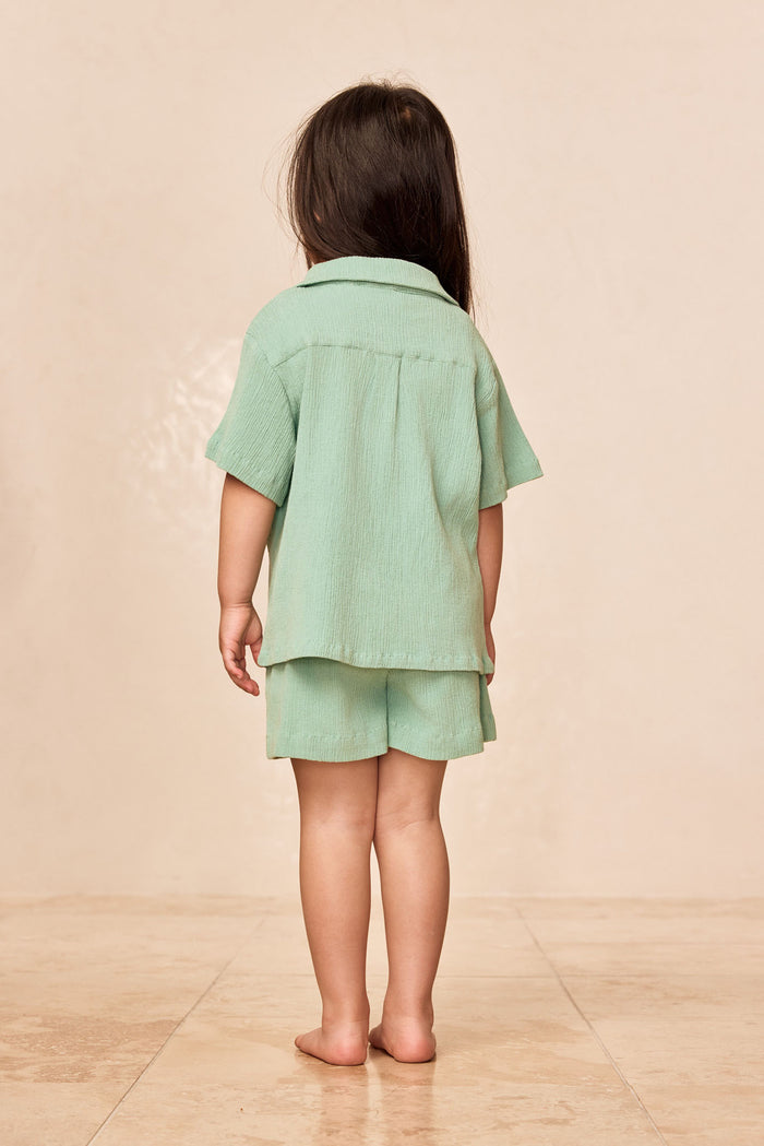 Back view of Pacific Beach Shirt Kids in Pond Crinkle showing crinkled texture, camp collar and short sleeves on neutral backdrop
