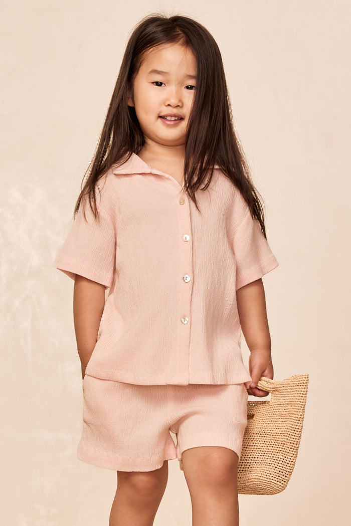 Front view of Pacific Beach Shirt Kids in Powder Pink Crinkle showing short sleeves, button-front crinkled fabric on a child model with relaxed fit against a neutral background