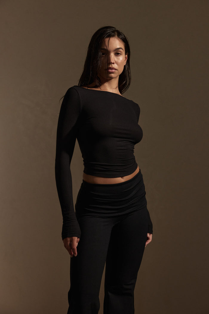 Three-quarter front of Paddington Long Sleeve in black rib showing fitted silhouette, long sleeves, on brown backdrop