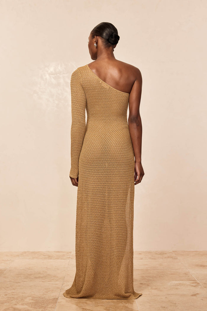 Back view of Palermo Dress in antique gold crochet, showing one-shoulder, long sleeve and textured knit on beige background