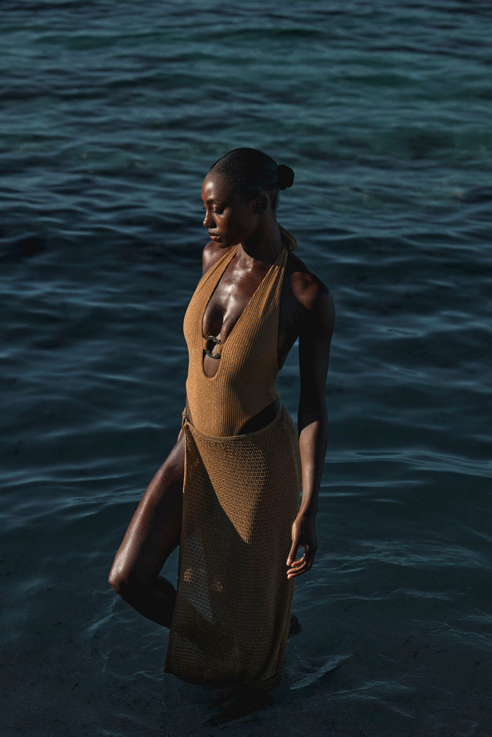 Three-quarter view of Palermo skirt in antique gold crochet with side tie and sheer midi knit on model in dark ocean water