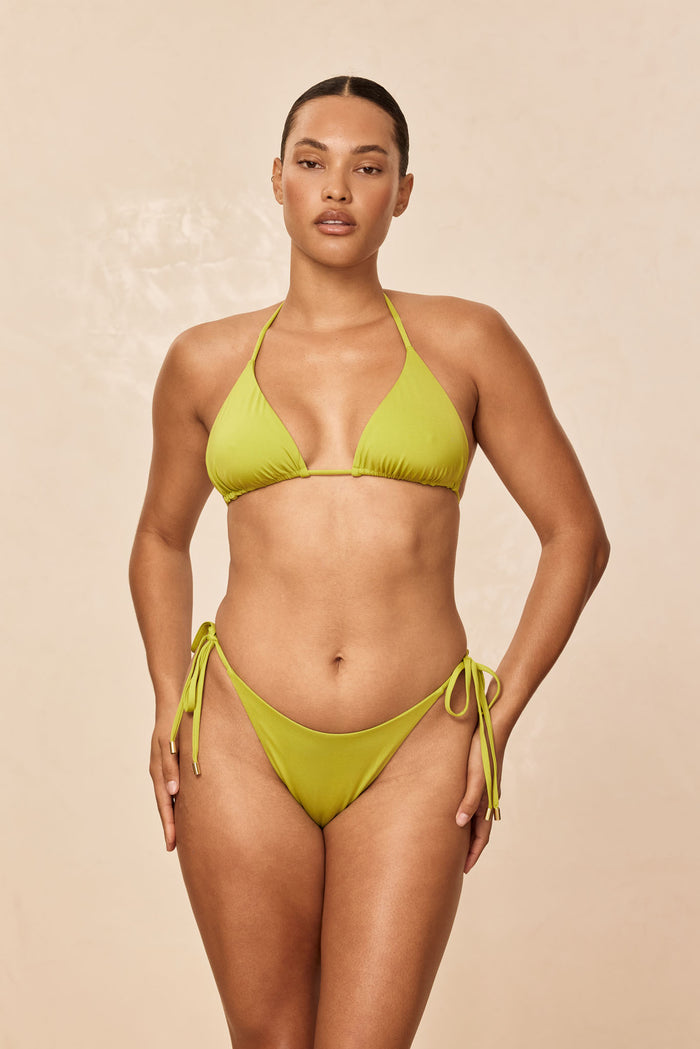 Front view of Palma Top in Apple on model, triangle bikini top with adjustable halter neck and back ties, beige background