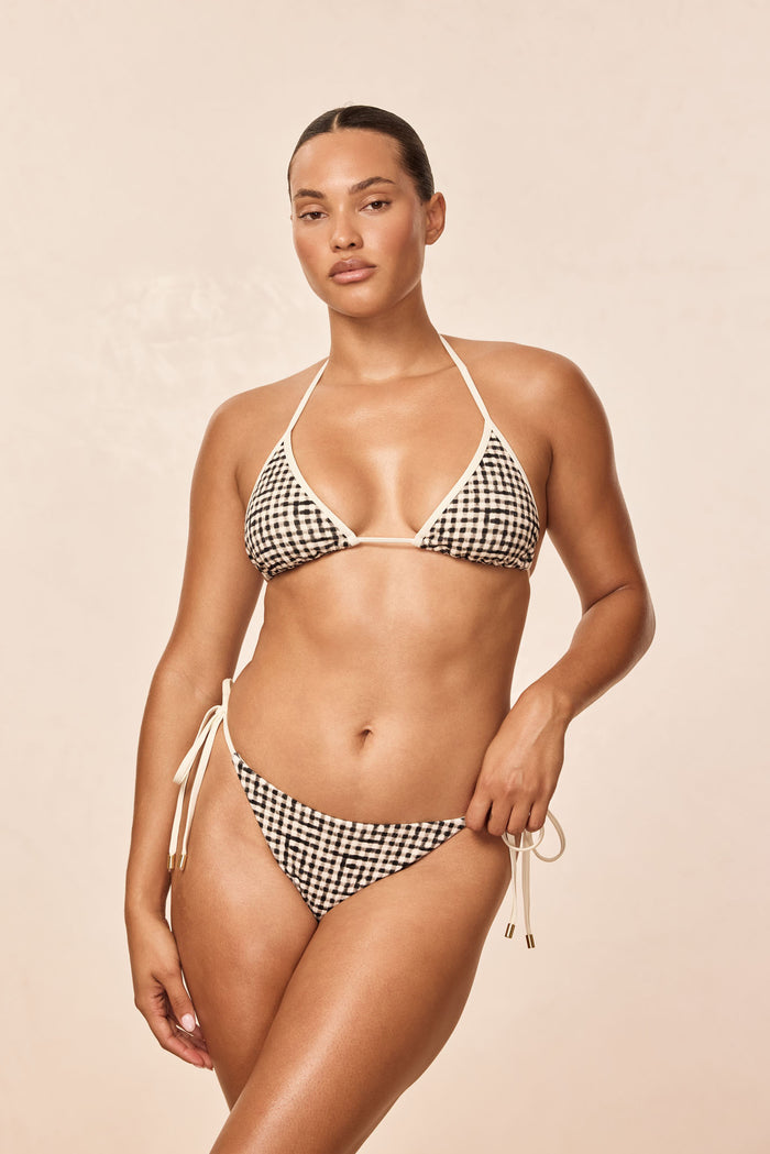 Front view of Palma Bottom in black gingham on model, tie-side adjustable bottoms with moderate coverage against a light beige studio background
