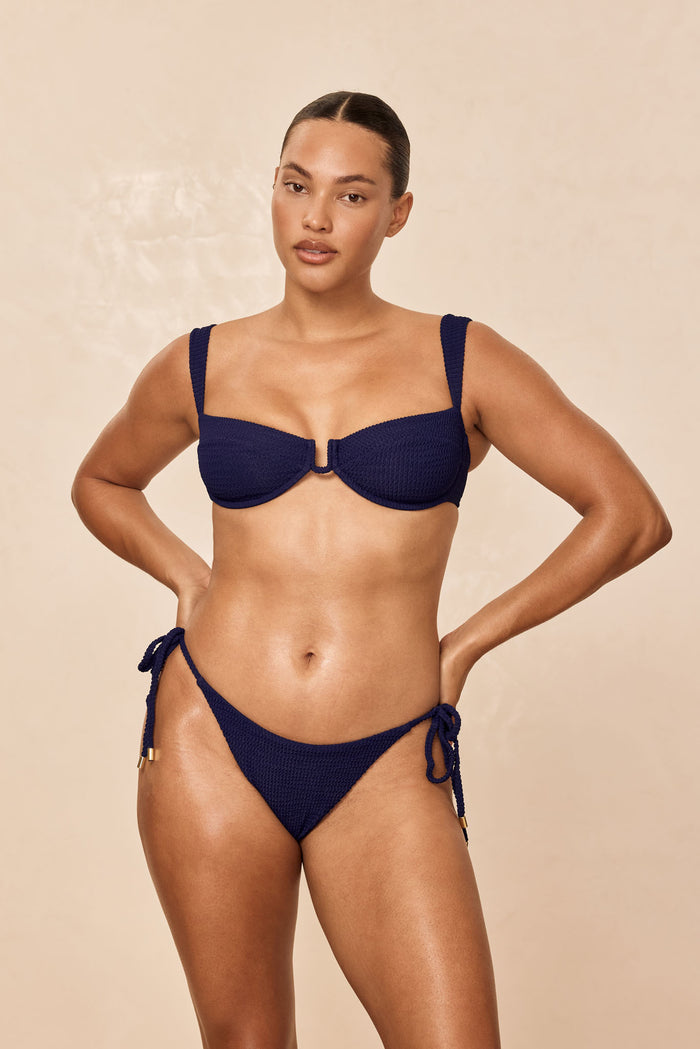 Front view of Palma Bottom in Midnight Crinkle showing crinkle texture, low-rise cut and adjustable tie sides on a beige background