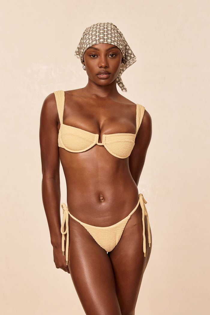 Front view of Palma Bottom in Raffia Crinkle showing mid-rise minimal coverage, adjustable ties with gold hardware, beige background