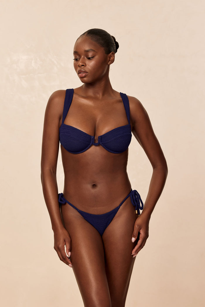 Front view of Palma Thong in Midnight Crinkle showcasing tie-side minimal-coverage thong on model with beige background