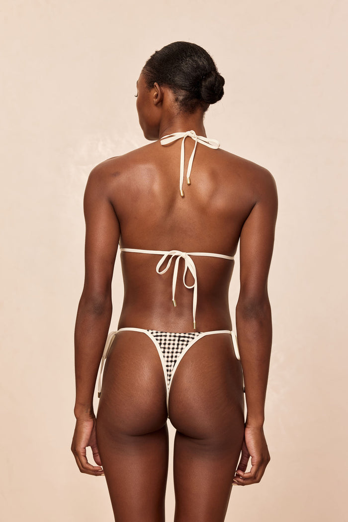 Rear view of Palma Thong in Black Gingham showing high-cut thong fit, tie-side strings, and cream top ties on beige background