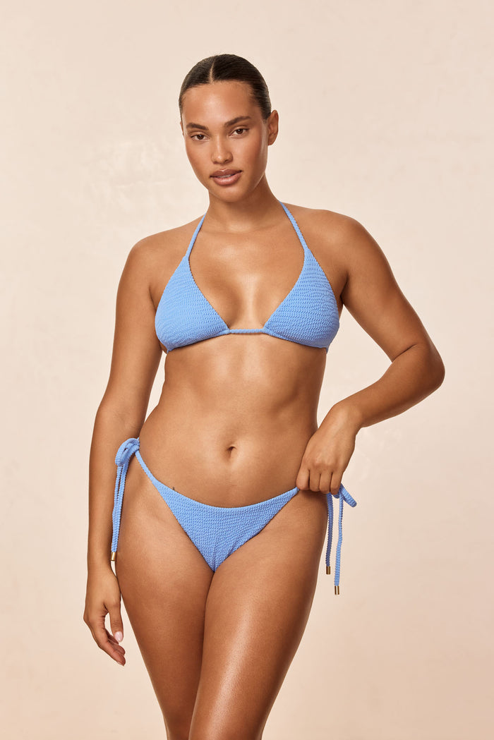 Front view of Palma Bottom in Azure Crinkle on model, low-rise tie-side with textured fabric, beige background