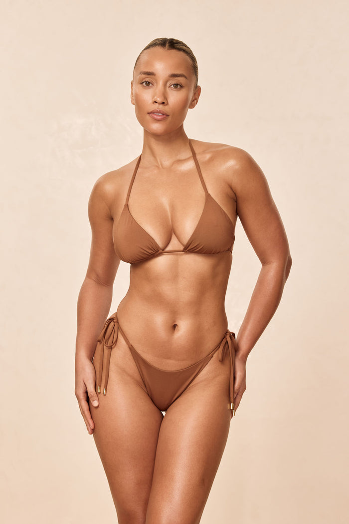Front view of Palma Top in Caramel on model showing triangle cups and adjustable halter ties with beige background