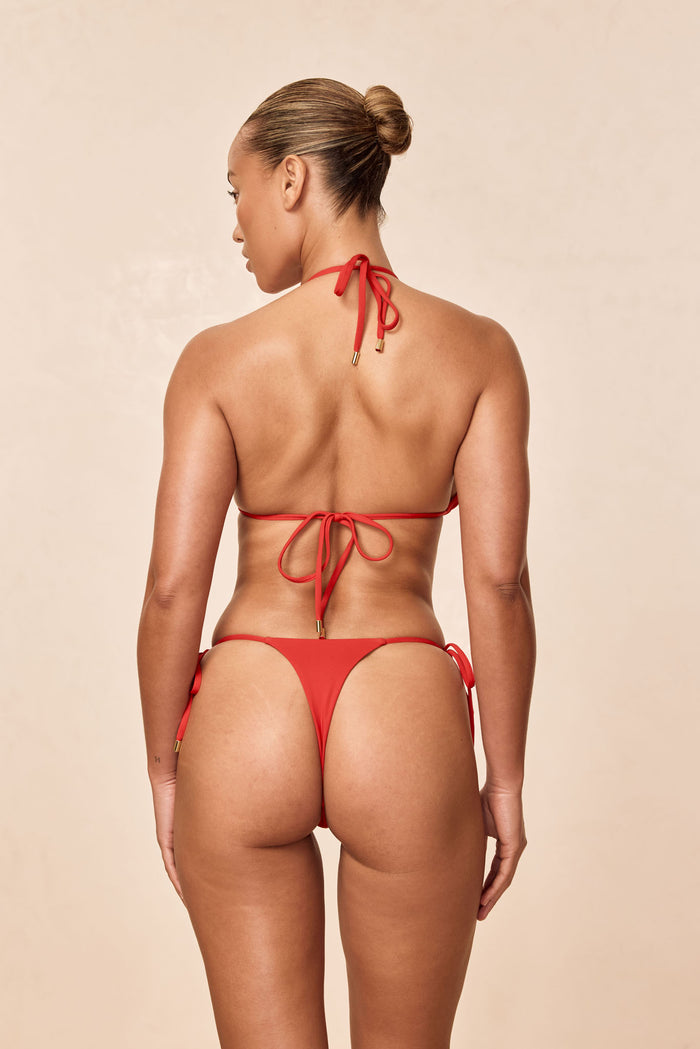 Rear view of Palma Top in chili pepper showing halter neck and tie-back with gold end caps on neutral studio background